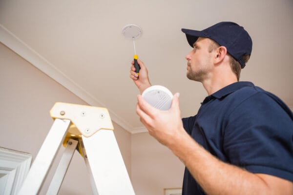 Electrician maintaining smoke alarm