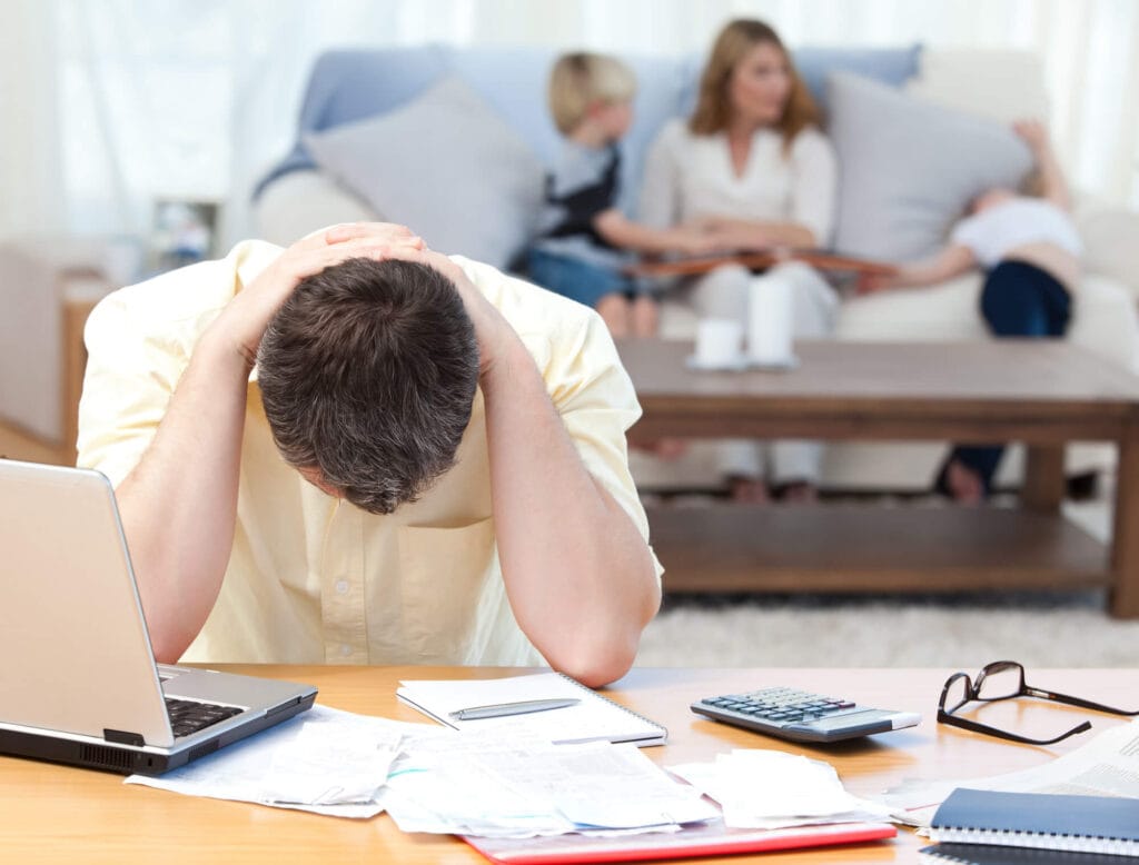 Man calculating his bills while his family are on the sofa — Photo