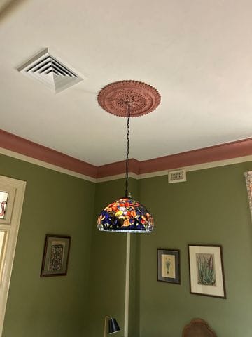 Decorative coloured pendant light hanging from an ornate ceiling rose.